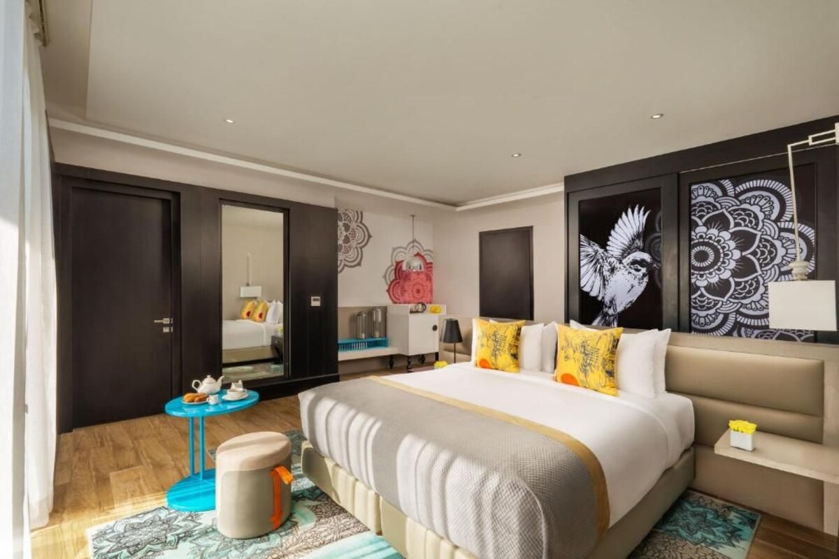 Una habitación de hotel moderna con una cama grande, una pequeña mesa redonda y un sofá.
