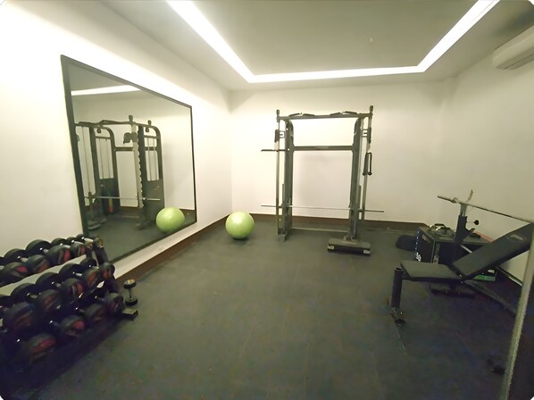A gym with exercise equipment, a mirror, and a treadmill. - Norbu The Montanna, Dharamshala - Ihcl Seleqtions (Dharamshala)