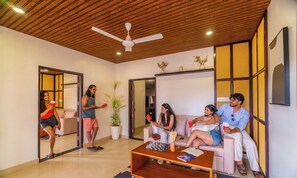 A modern living room with a ceiling fan, a coffee table with a chessboard, and a sofa. - Zo Selections Gokarna by Zostel (Gokarna)