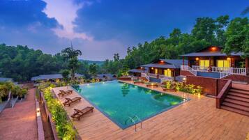 A resort with a swimming pool, wooden deck, and multiple guest villas.
