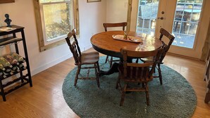 A dining area with a wooden table and chairs, surrounded by large windows with a view of trees and a building outside. - Serene 3-bedroom bungalow with AC in charming Canton (Canton)