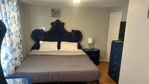 A bedroom with a large bed, a dresser, a chair, and a bedside table with a lamp. - Grove 3 (Irvington)