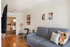 A living room with a grey sofa, a television, and artwork on the wall.