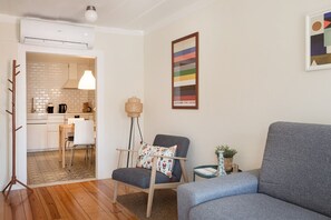 A modern living room with a grey sofa, a patterned armchair, and a dining area with a white table and chairs. - Bright Alfama Studio with AC (Lisbon)