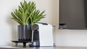 A coffee machine on a table with a potted plant beside it.
