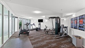 A gym with cardio machines, weightlifting equipment, and a large window.