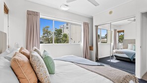 Ein Schlafzimmer mit einem großen Bett, Blick ins Freie und einem Balkon.