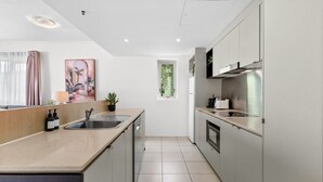 Una cocina moderna con una isla central, electrodomésticos de acero inoxidable y vistas al exterior.