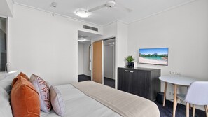 A hotel room with a bed, bedside table, desk, chair, and a TV on the wall. - Aveline Dual-Key at Mantra Trilogy | Pool & Gym Steps to Esplanade (Cairns City)