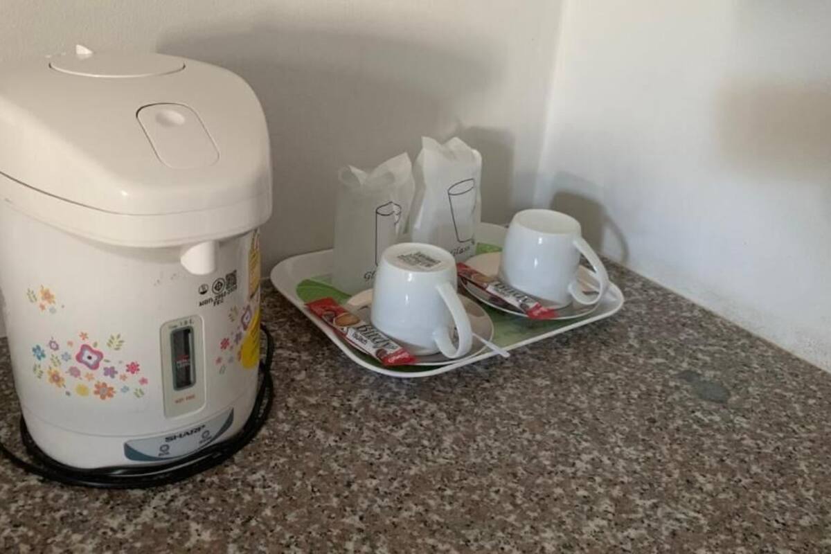 Eine Kaffeemaschine mit Stromkabel, zwei weiße Tassen und eine Ablage mit Kaffeepads auf einer Granitabdeckung.