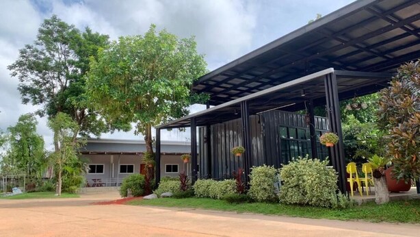 A modern building with a covered entrance, surrounded by lush greenery and trees. - Easarninn Yasothorn (Yasothon)