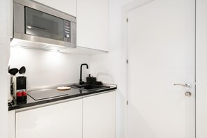 A compact kitchen with a built-in microwave, a sink, and a small countertop. - Dobohomes D14 (Madrid)