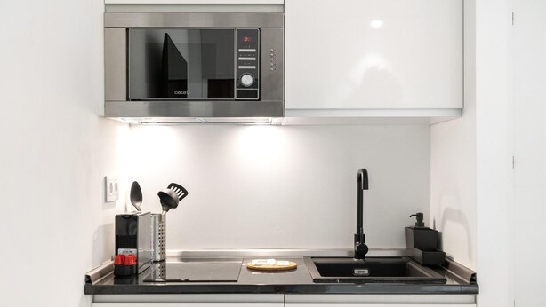 A compact kitchen with a microwave, sink, and basic utensils. - Dobohomes D14 (Madrid)