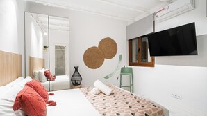 A modern bedroom with a bed, a TV, a mirror, and a wall-mounted air conditioner. - Dobohomes D14 (Madrid)