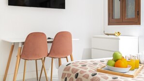 A dining area with a table set for two, featuring a fruit bowl and glasses of orange juice. - Dobohomes D14 (Madrid)