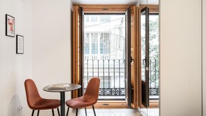 A room with a wooden-framed window, two brown chairs, and a small round table. - Dobohomes D14 (Madrid)
