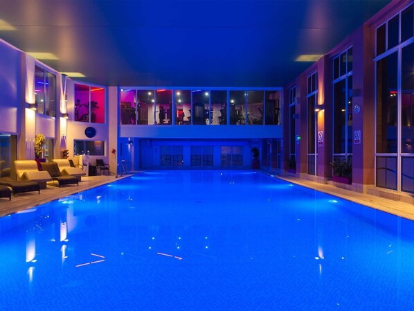A swimming pool with lounge chairs and a glass-enclosed upper level with seating. - Forest Pines Spa and Golf Resort (Brigg)