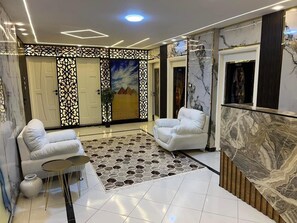 A modern lobby with two white sofas, a patterned rug, and marble walls. - Miracle Pyramids Hotel (Giza)