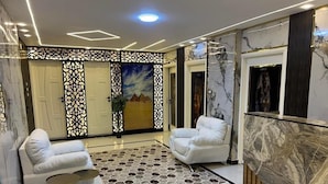Eine moderne Lobby mit zwei weißen Sofas, einem gemusterten Teppich und Marmorwänden.