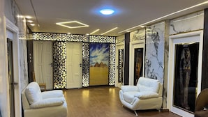 Ein geräumiges Zimmer mit zwei weißen Ledersofas, Holzboden und einer Wand mit Wandmalerei.