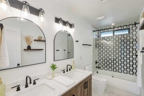 A modern bathroom with a double sink, two mirrors, a shower with a geometric tile pattern, and a toilet. - Element By Avantstay Pool Firepit Game Room (Scottsdale)
