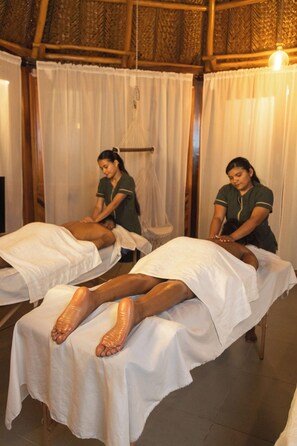 A room with two massage tables covered with white sheets, a wooden ceiling, and a hanging light fixture. - Zirwa Hotel Boutique (Santa Marta)