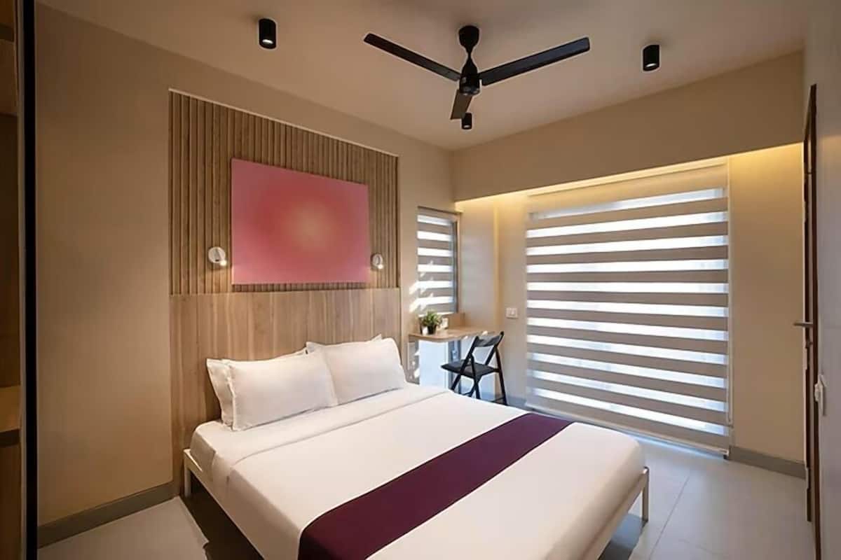 Ein modernes Schlafzimmer mit einem Bett, einem Deckenventilator und einem großen Fenster mit Jalousien.