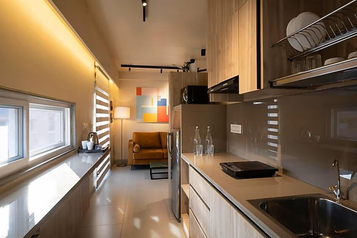 A modern kitchen with a built-in oven, a sink, and a dining area with a sofa and table.