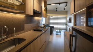 A modern kitchen with built-in appliances, a countertop sink, and a dining area with a sofa and coffee table. - Hotel PXL 27 (Bengaluru)