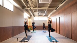 A yoga class in a room with wooden paneling, large windows, and a wooden floor. - Hotel PXL 27 (Bengaluru)