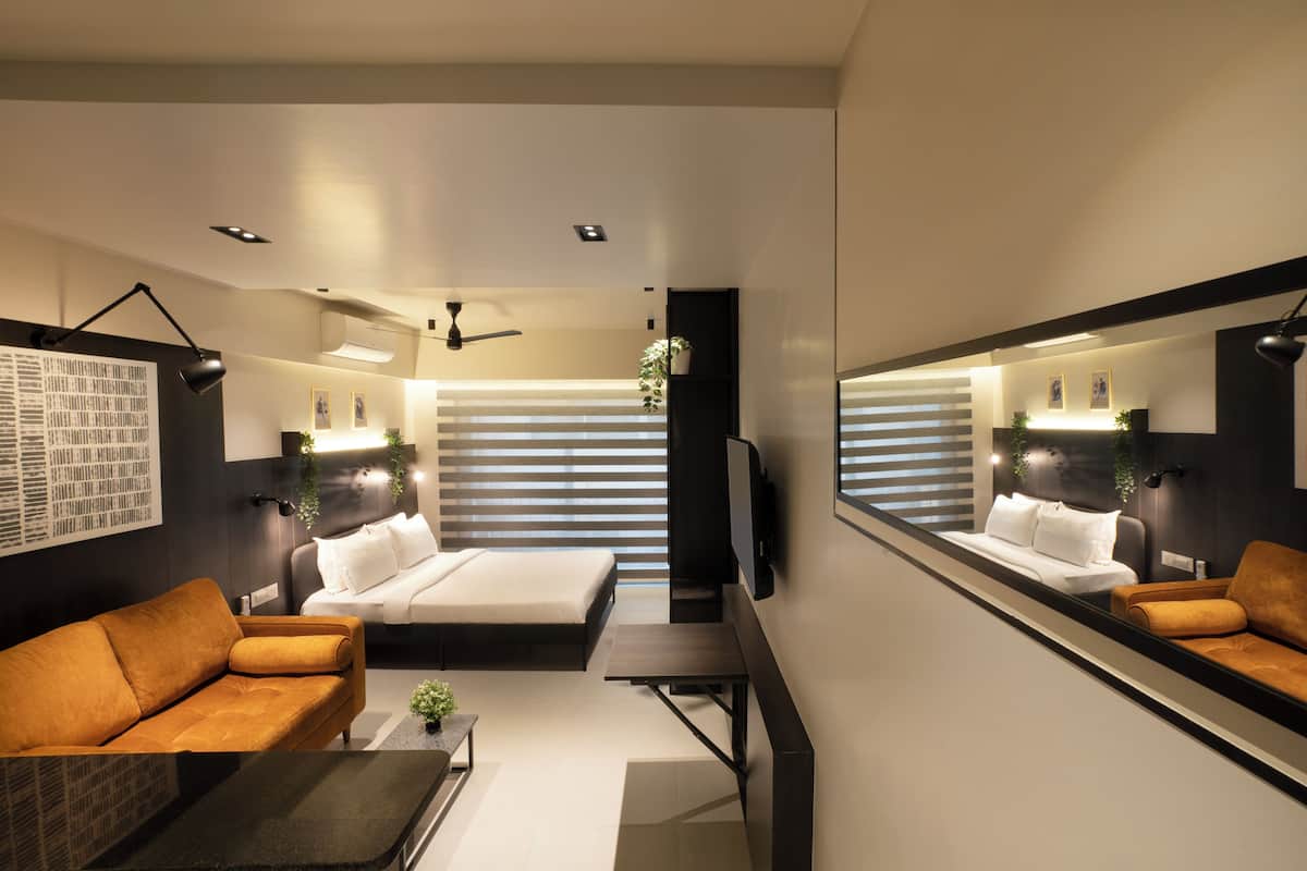 Ein modernes Schlafzimmer mit einem Bett, einer Couch, einem Schreibtisch und einem großen Spiegel.