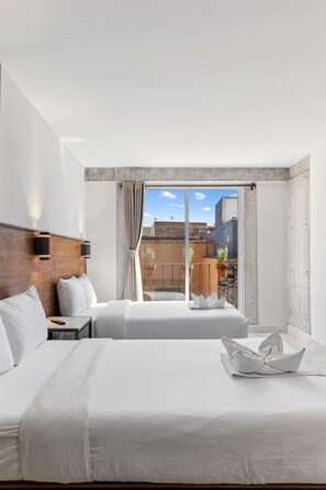 Une chambre d’hôtel moderne avec deux lits, une grande fenêtre donnant sur la ville et un mur décoratif en béton.