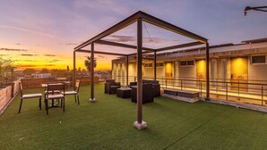 An outdoor seating area with a pergola, artificial grass, and a building with illuminated windows. - Morelos By Homirent (Cadereyta de Montes)