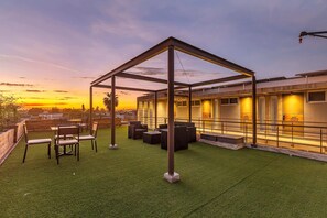 An outdoor seating area with a pergola, artificial grass, and a building with illuminated windows. - Morelos By Homirent (Cadereyta de Montes)