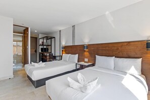 Een hotelkamer met twee bedden, een houten hoofdeinde, een klein bureau en een boekenplank.