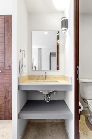 Een badkamer met een wit wastafelmeubel, een spiegel en een toilet.