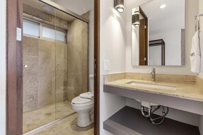 Une salle de bain moderne avec une douche à parois de verre, des toilettes blanches et un meuble-lavabo avec un lavabo et un miroir.