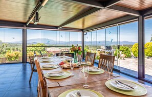 A dining area with a table set for four, large windows, and a view of the countryside.