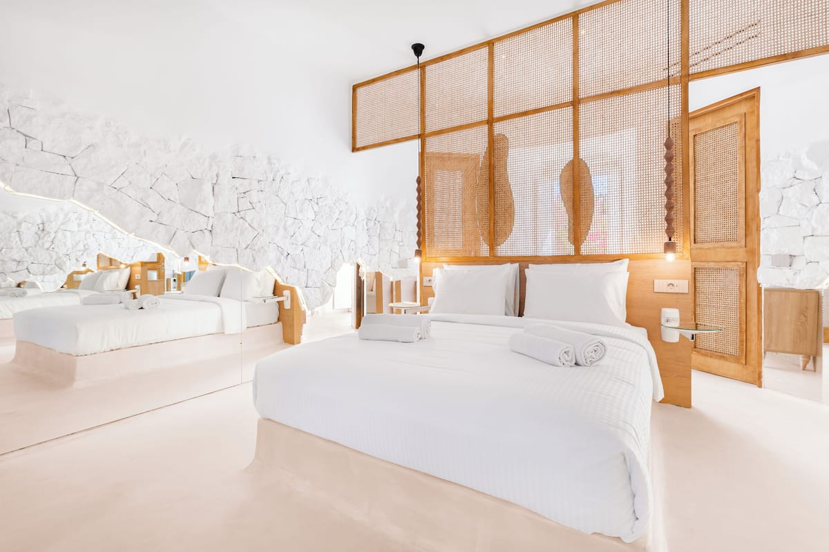 A modern hotel room with a large bed, a smaller sofa, and a wooden partition.