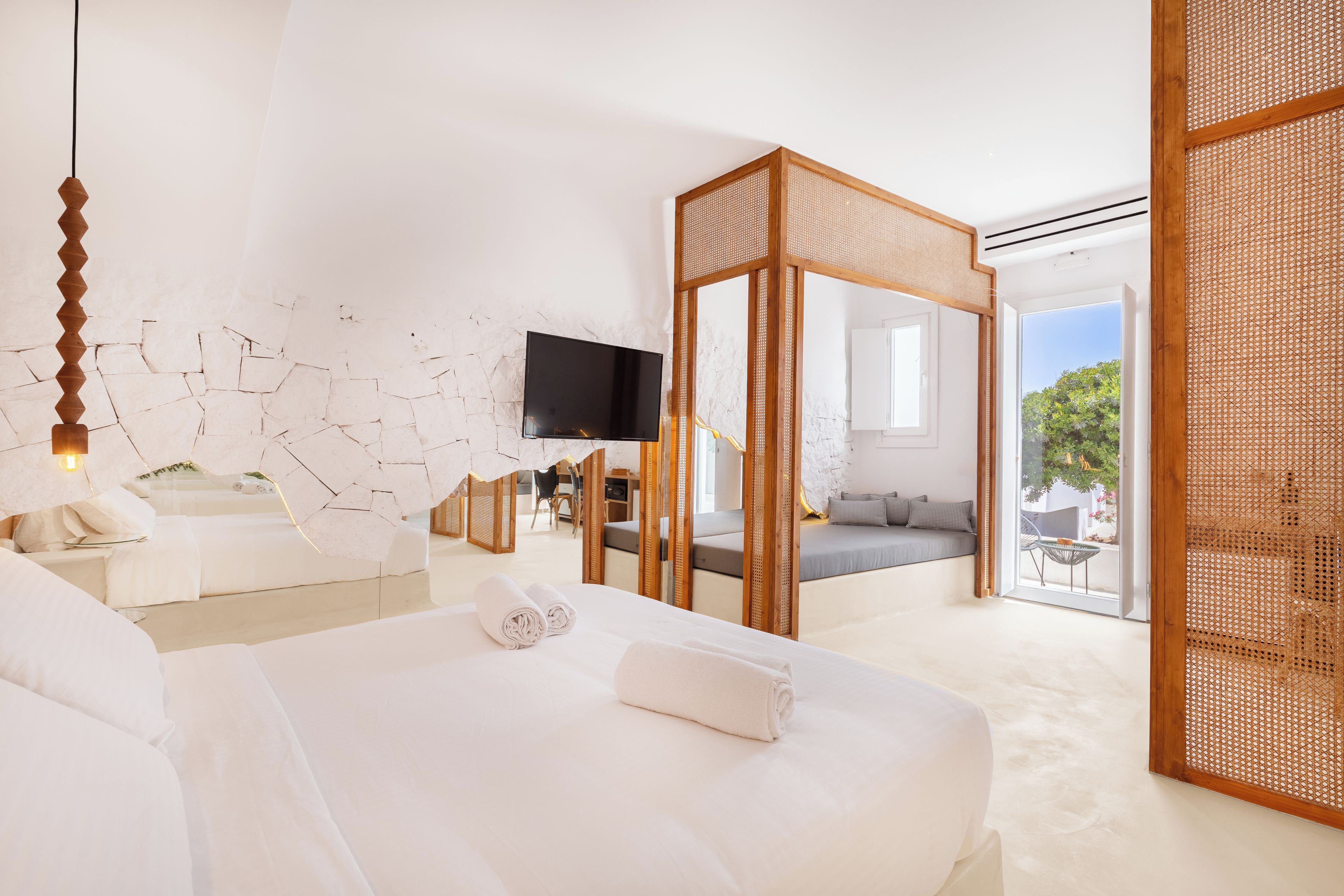 Habitación de hotel moderna con una cama grande, televisión, balcón y vistas al exterior.