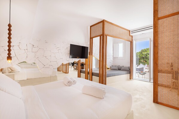 A modern hotel room with a large bed, a TV, a balcony, and a view of the outdoors. - Anome Hotel (Mykonos)