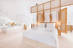 A modern hotel room with a large bed, a smaller sofa, and a wooden partition. - Anome Hotel (Mykonos)