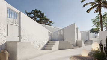 Diseño arquitectónico moderno con una escalera que lleva a un edificio blanco, rodeado de cactus y una palmera.