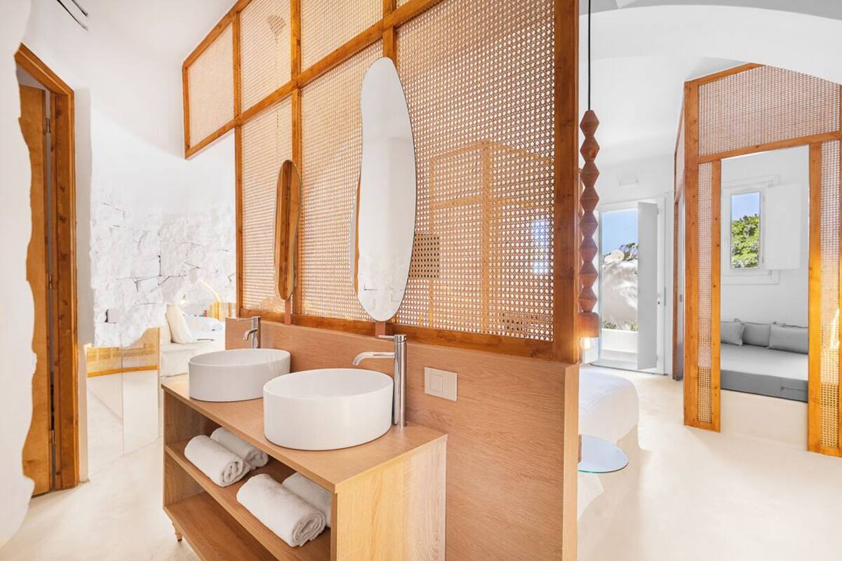 A modern bathroom with two round sinks, wooden shelving, and a large mirror.