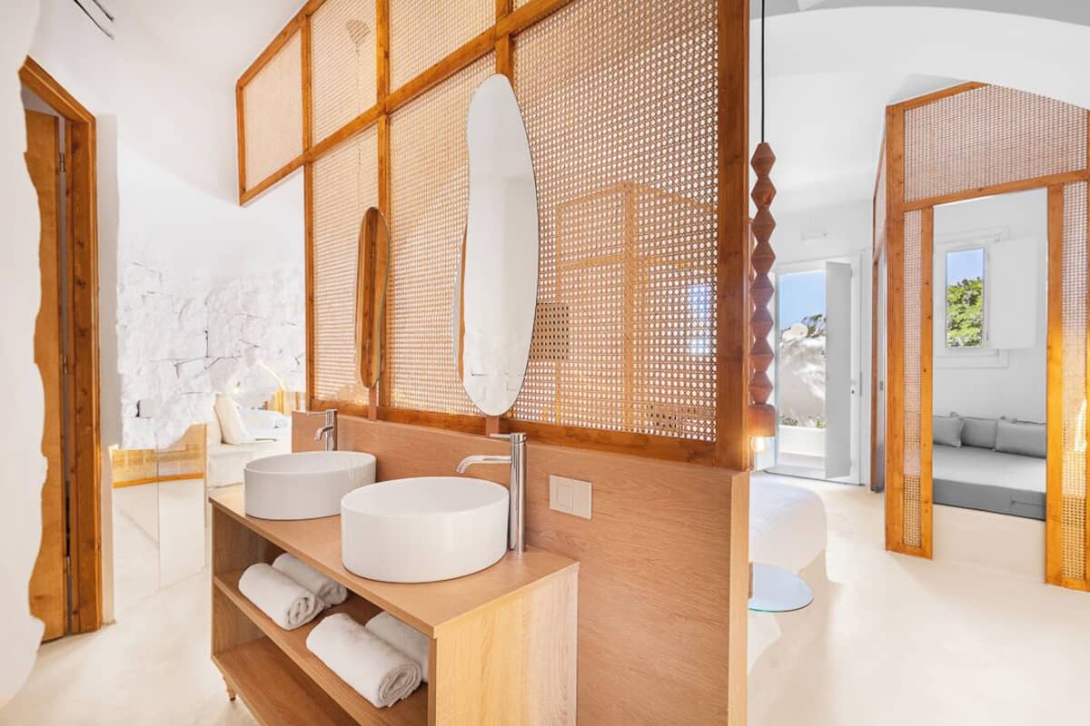 A modern bathroom with two round sinks, wooden shelving, and a large mirror.