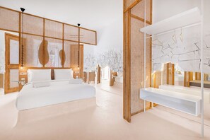 Moderni hotellihuone, jossa on suuri sänky, puinen väliseinä ja valkoinen konsolipöytä.