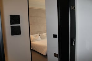 A hotel room with a bed, a door with a keypad lock, and two framed pictures on the wall. - Sparano Palace_luxury Maison (Bari)