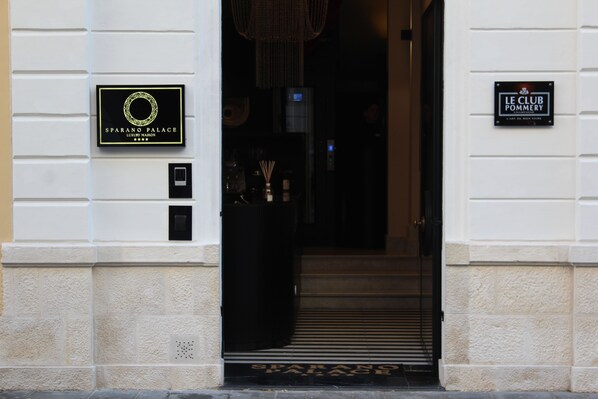 La entrada a un edificio con un letrero que dice 'SPARANO PALACE LUXURY MAISON' y otro letrero que indica 'LE CLUB POMMERY'.