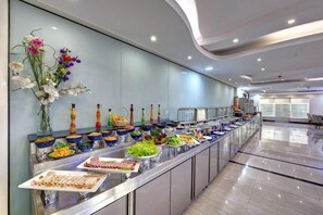 A buffet setup with various food items and a decorative vase of flowers. - City Stay Hotel Expo Center Sharjah (Sharjah)