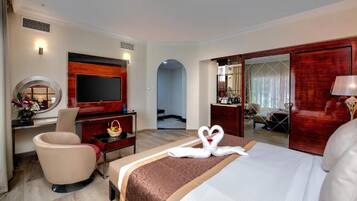 A hotel room with a large bed, a TV, a desk with a chair, and a mirror.